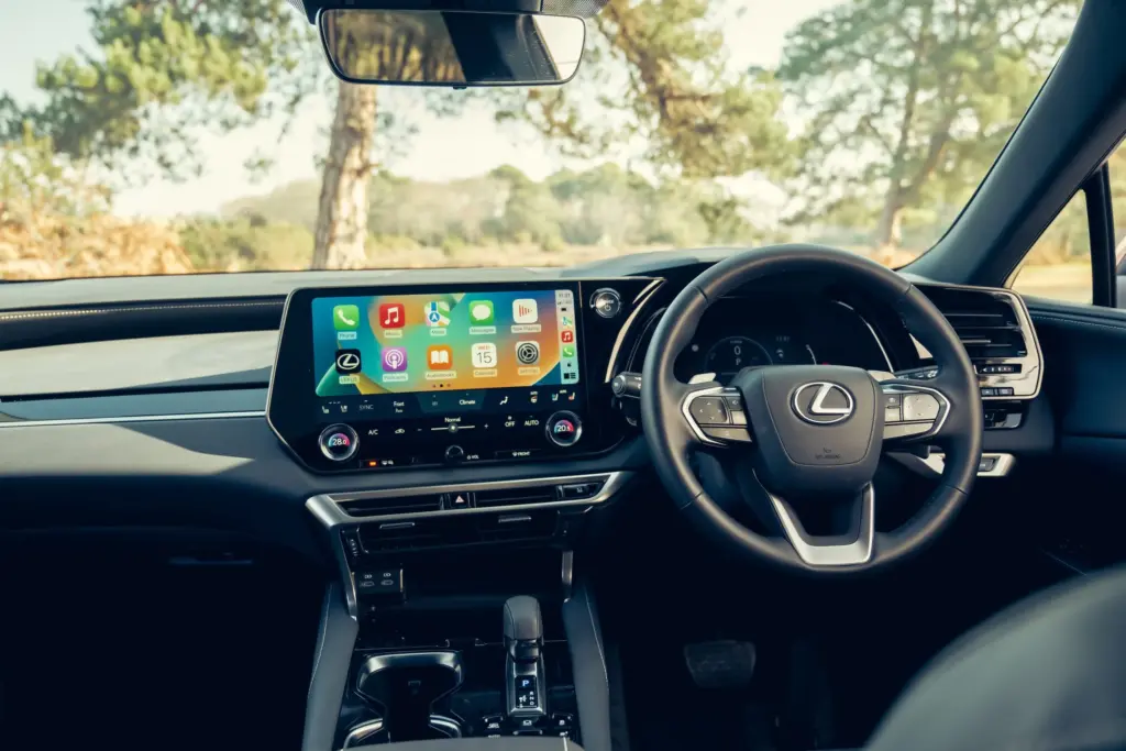 Lexus RX 450h+, cabine da versão internacional; volante, acabamento e equipamentos podem diferir no Brasil.